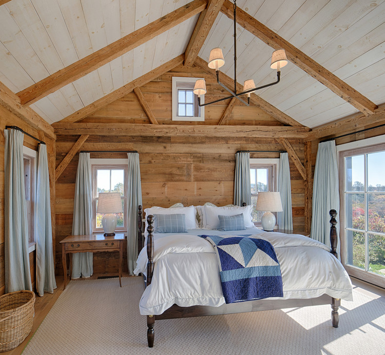 Modelo de dormitorio principal rural de tamaño medio sin chimenea con paredes marrones, suelo de madera clara y suelo marrón