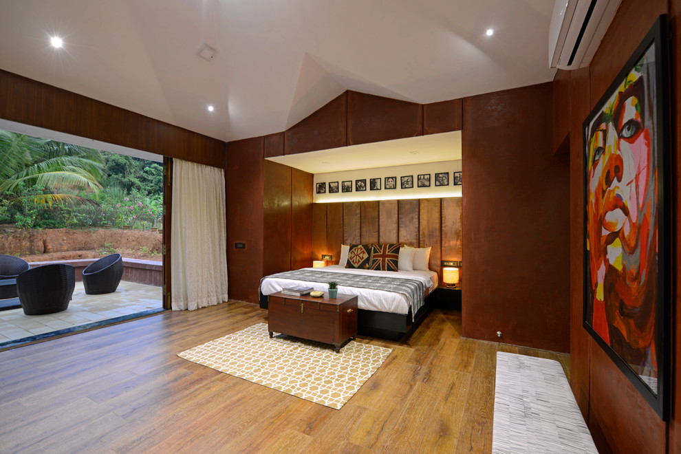 Foto de dormitorio actual grande con paredes marrones, suelo de madera en tonos medios y suelo marrón