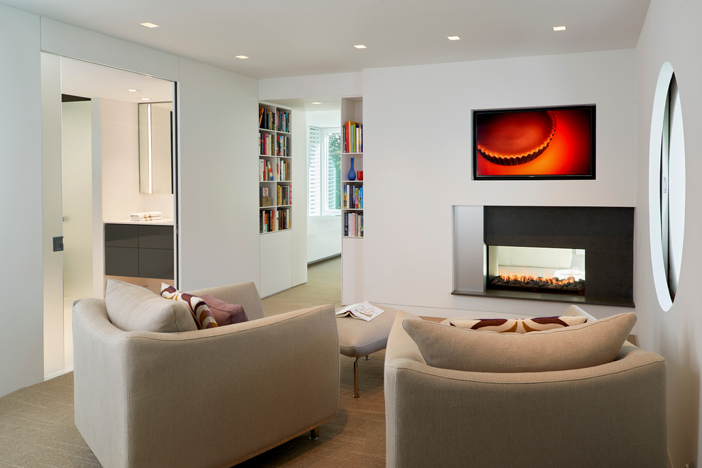 This is an example of a contemporary master bedroom in DC Metro with white walls, carpet and a two-sided fireplace.