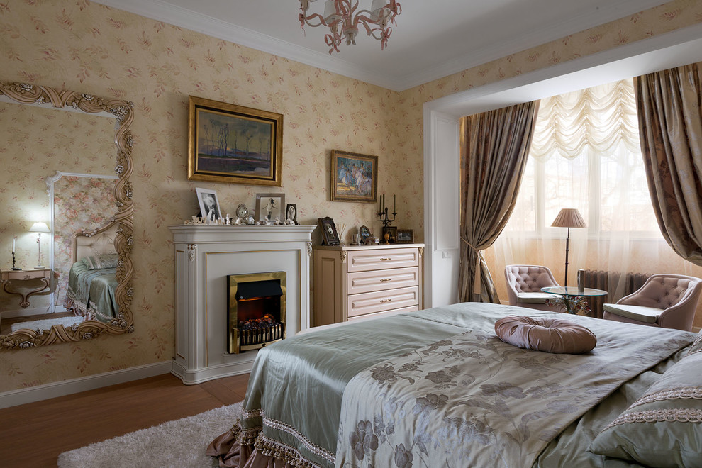 This is an example of a medium sized traditional bedroom in Other with beige walls, medium hardwood flooring and a standard fireplace.