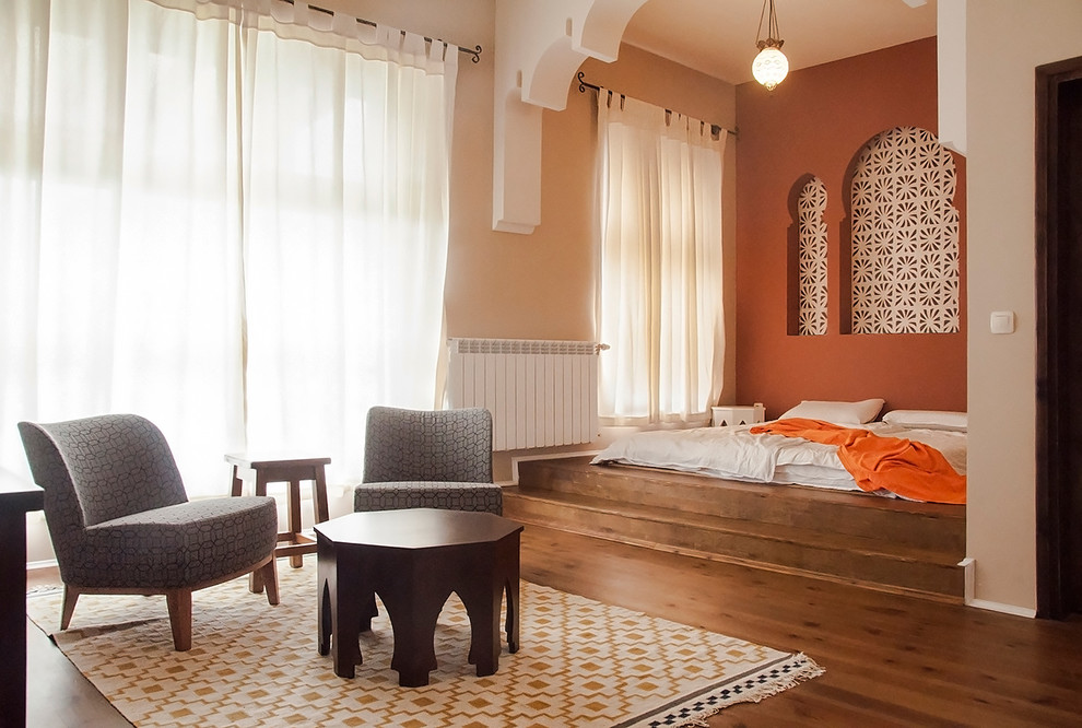 Immagine di una camera matrimoniale etnica di medie dimensioni con pareti arancioni e parquet chiaro