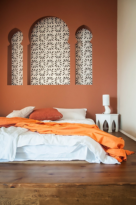 Ispirazione per una camera matrimoniale etnica di medie dimensioni con pareti arancioni e parquet chiaro