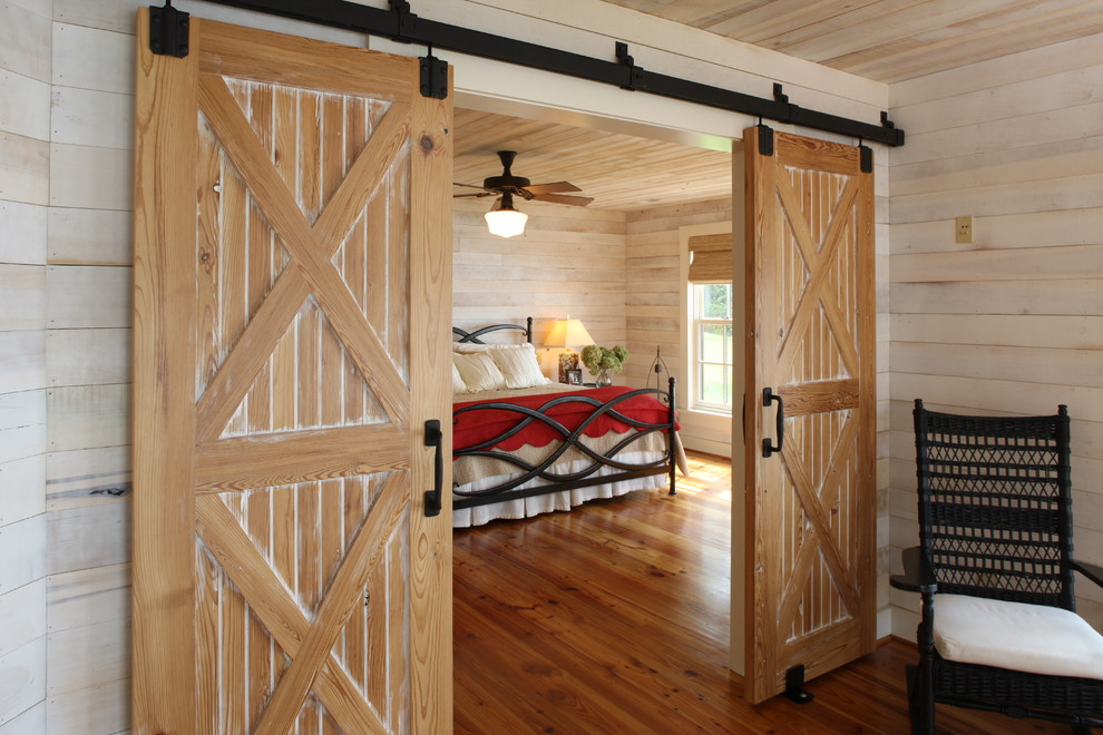 Modelo de dormitorio principal de estilo de casa de campo grande sin chimenea con paredes beige, suelo de madera oscura y suelo marrón