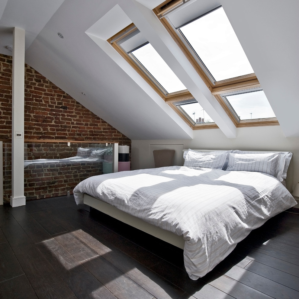 Ejemplo de dormitorio tipo loft actual con paredes blancas, suelo de madera oscura y techo inclinado