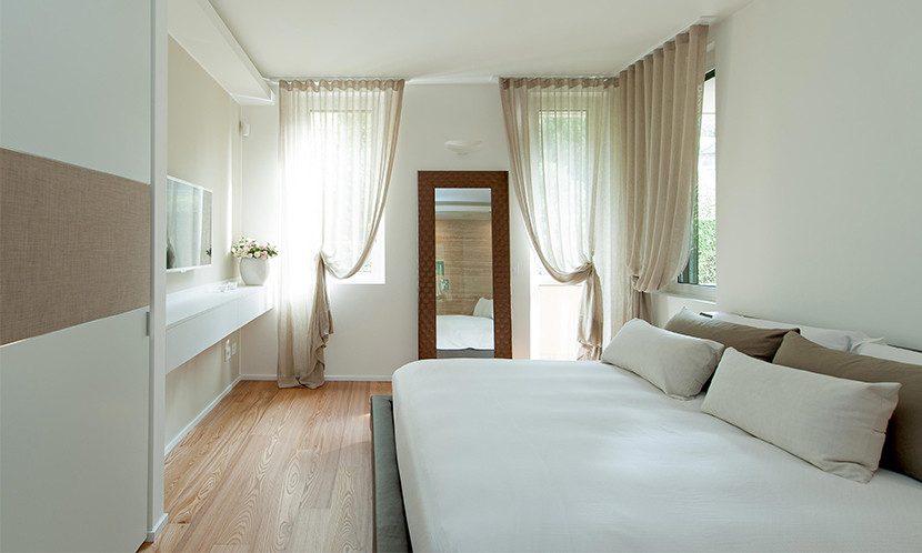 Photo of a small contemporary master bedroom in Milan with white walls and medium hardwood flooring.