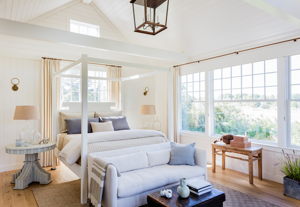 Diseño de dormitorio principal costero grande sin chimenea con paredes blancas, suelo de madera en tonos medios y suelo marrón