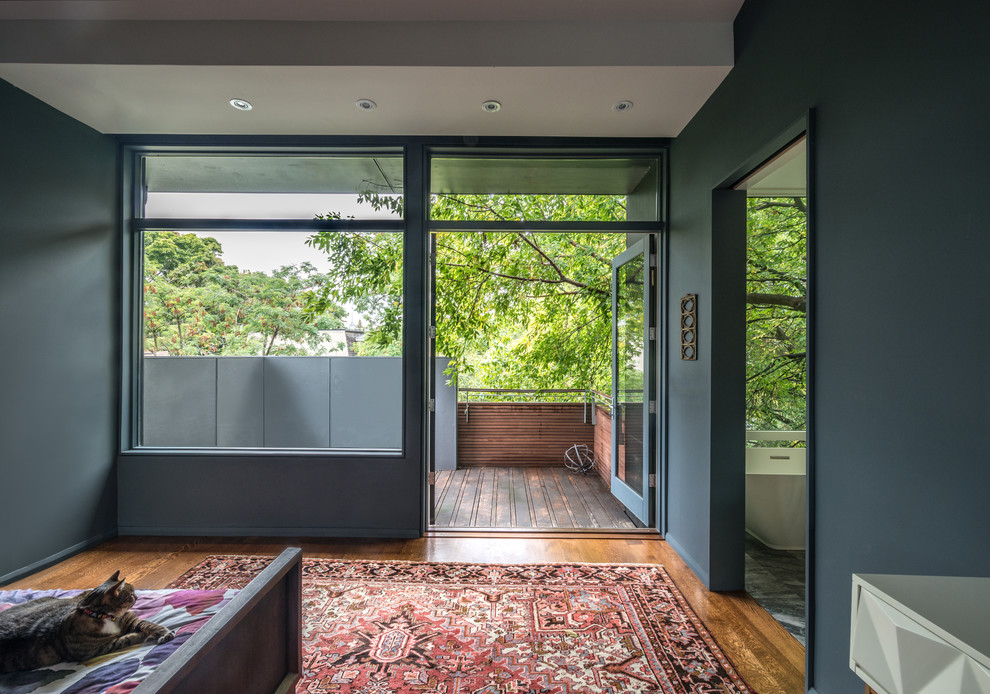 На фото: маленькая хозяйская спальня в современном стиле с серыми стенами, паркетным полом среднего тона, двусторонним камином, фасадом камина из камня и коричневым полом для на участке и в саду