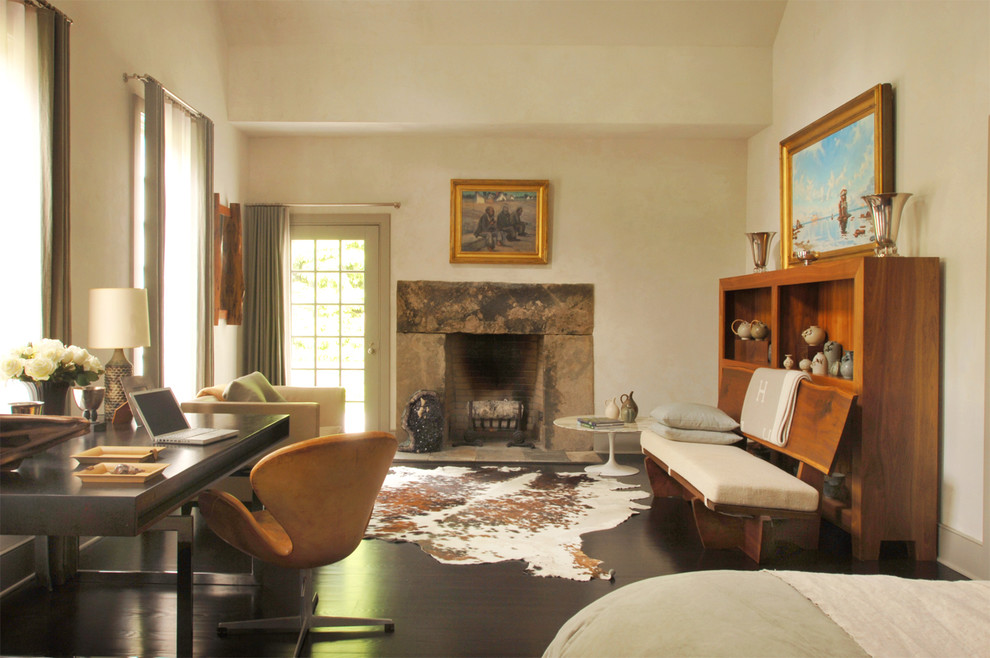 Imagen de dormitorio campestre con marco de chimenea de piedra y suelo marrón