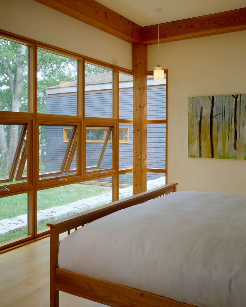 Medium sized modern master bedroom in Portland Maine with beige walls and light hardwood flooring.