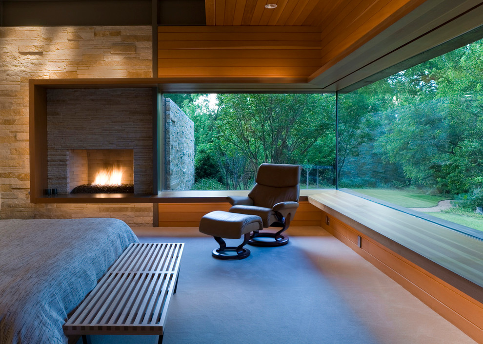 Modernes Hauptschlafzimmer mit Kamin, Kaminumrandung aus Stein und Teppichboden in Dallas