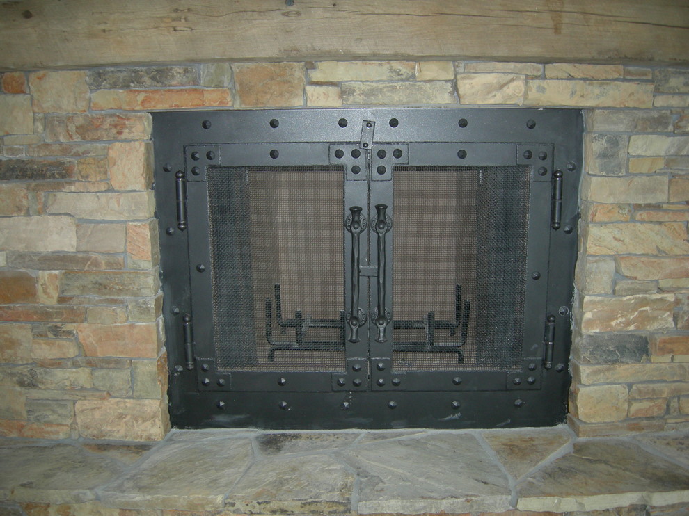 This is an example of a medium sized rustic master bedroom in Other with a wood burning stove and a stone fireplace surround.