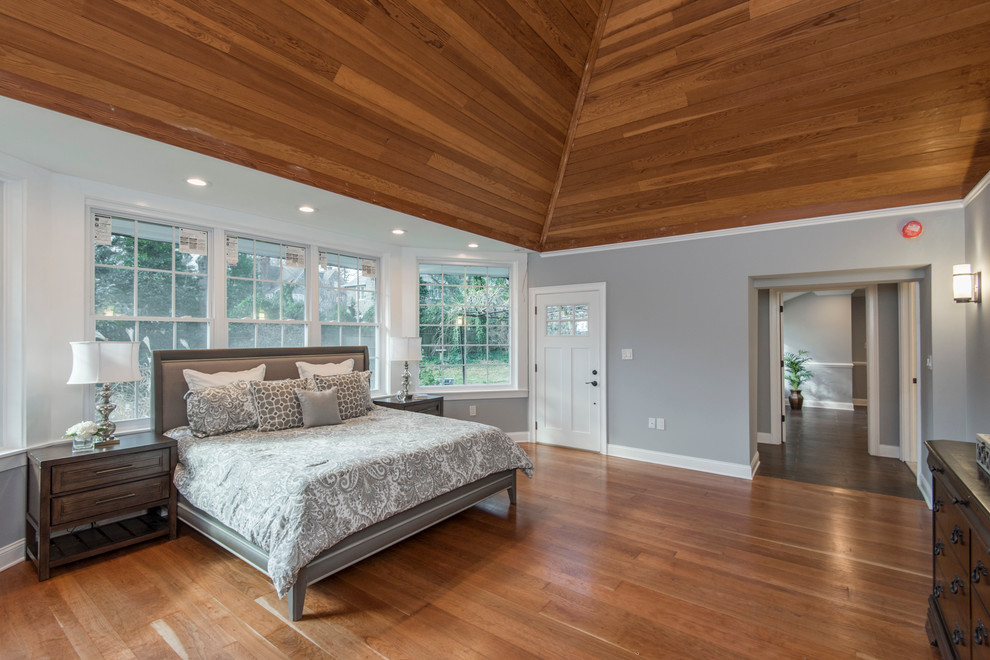 Ejemplo de dormitorio principal clásico grande sin chimenea con paredes grises, suelo de madera en tonos medios y suelo marrón