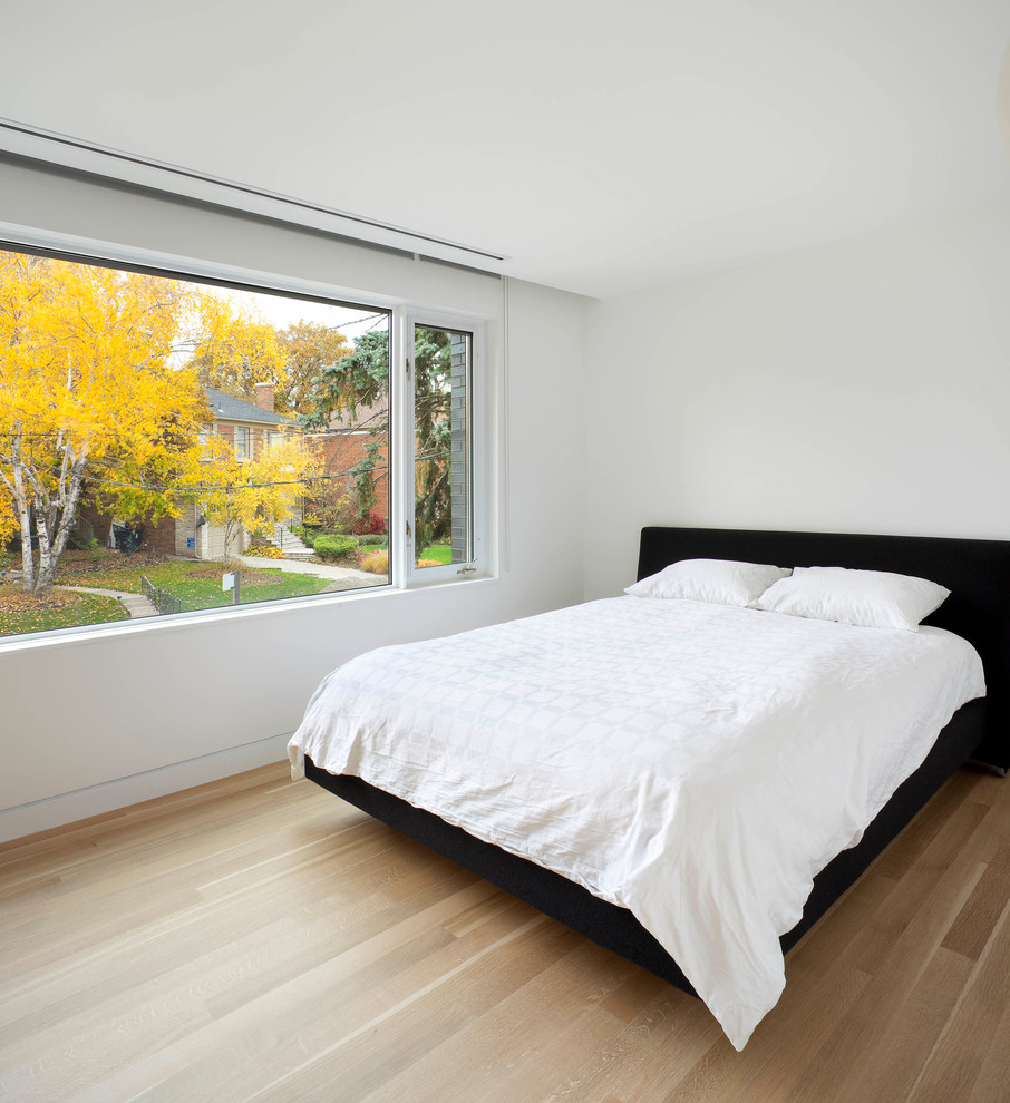 Cette image montre une chambre parentale minimaliste de taille moyenne avec un mur blanc, parquet clair, aucune cheminée et un sol beige.