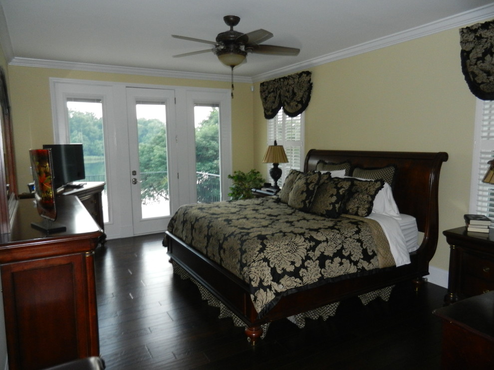 Mittelgroßes Klassisches Hauptschlafzimmer mit gelber Wandfarbe und dunklem Holzboden in Charleston