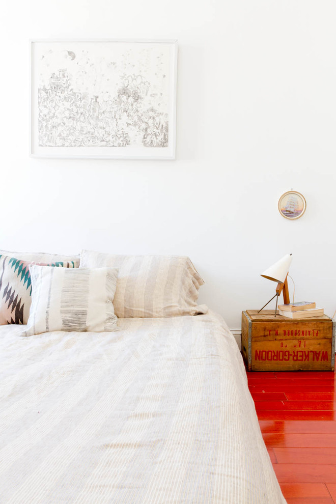 Modelo de dormitorio ecléctico con paredes blancas y suelo rojo