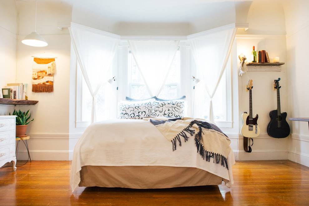 Immagine di una camera da letto bohémian con pareti bianche e pavimento in legno massello medio