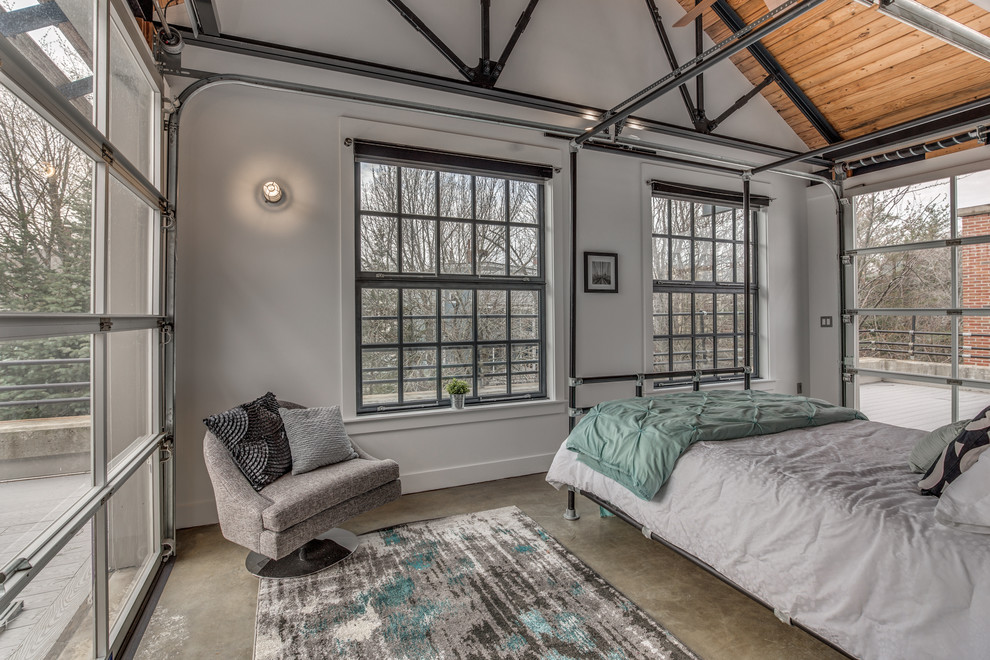 Photo of an industrial master bedroom in Boston with white walls and concrete flooring.