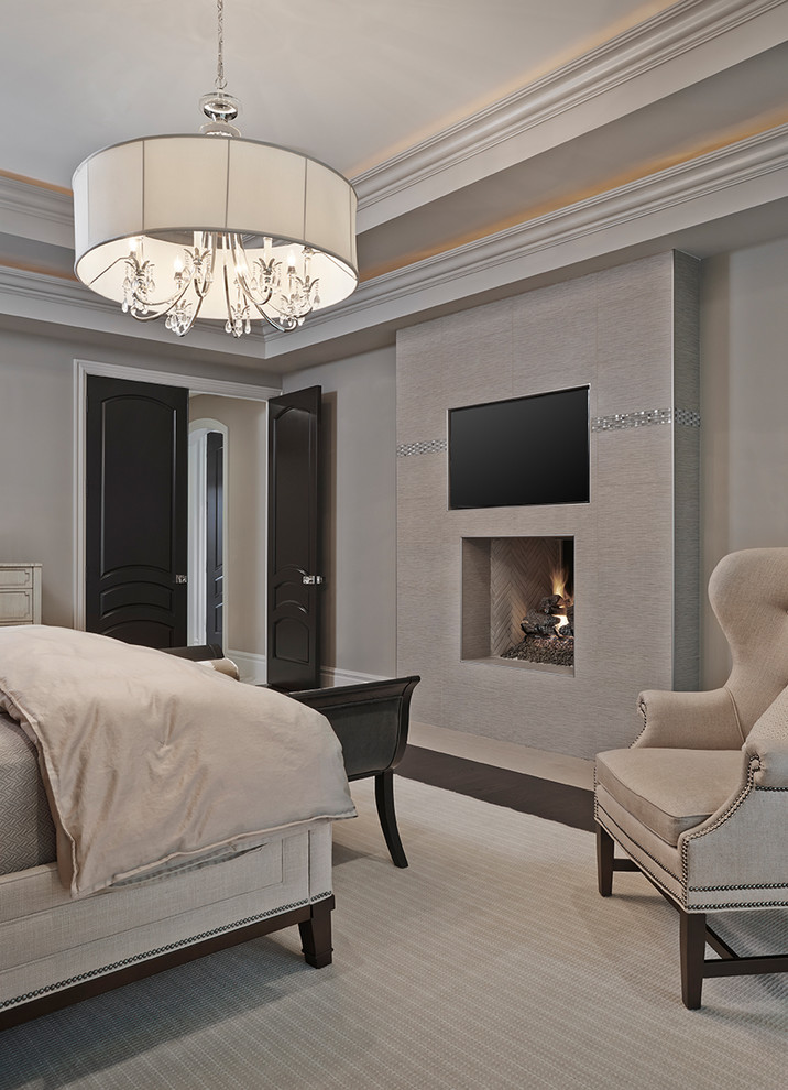 Imagen de dormitorio principal clásico renovado extra grande con paredes beige, suelo de madera oscura, marco de chimenea de piedra y todas las chimeneas