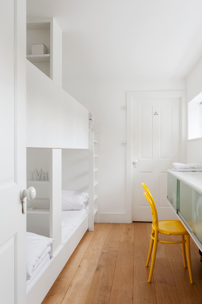 Foto di una piccola camera degli ospiti scandinava con pareti bianche, pavimento in legno massello medio e nessun camino