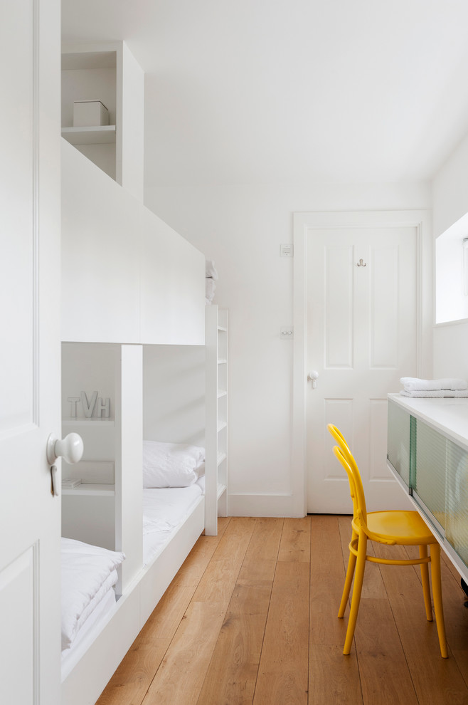 Idées déco pour une petite chambre d'amis scandinave avec un mur blanc, un sol en bois brun et aucune cheminée.