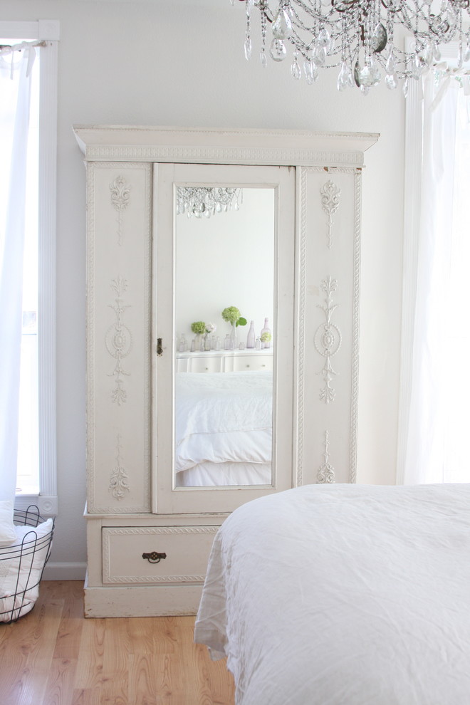 Photo of a vintage bedroom in Other with white walls and light hardwood flooring.