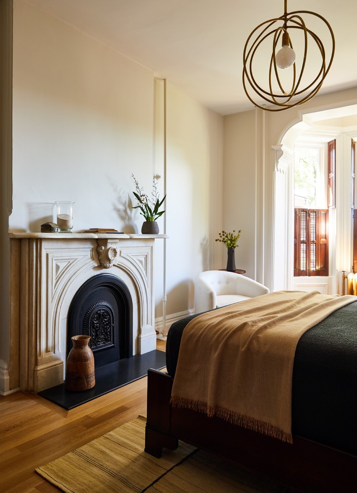 Idee per una camera da letto tradizionale con pareti beige, pavimento in legno massello medio, camino classico e pavimento marrone