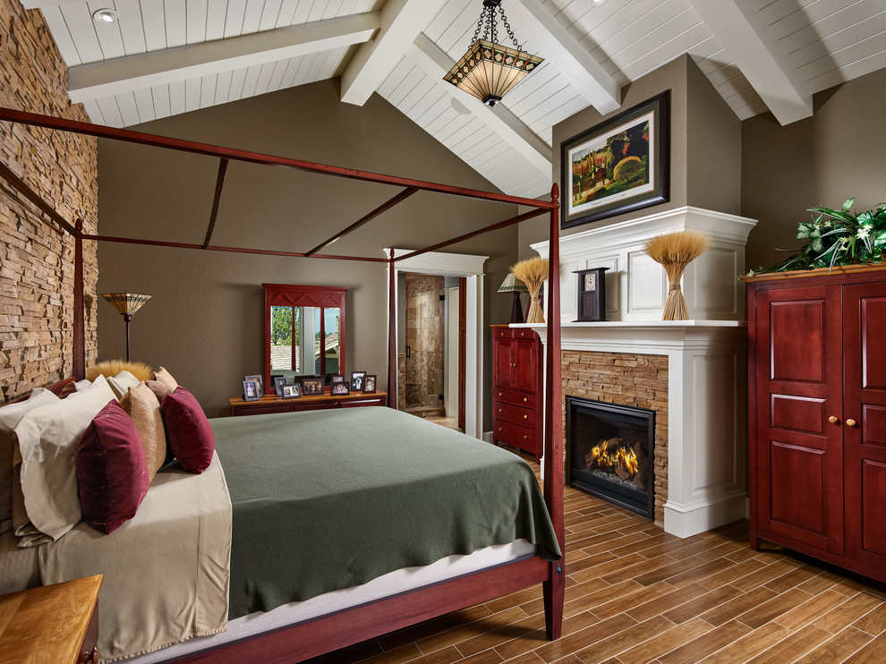 Design ideas for a classic master bedroom in Denver with brown walls, a standard fireplace, a stone fireplace surround, brown floors and a chimney breast.