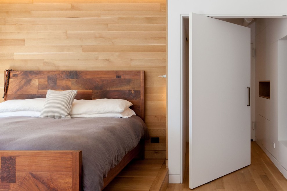 Ejemplo de dormitorio principal moderno de tamaño medio sin chimenea con paredes blancas, suelo de madera clara y suelo marrón