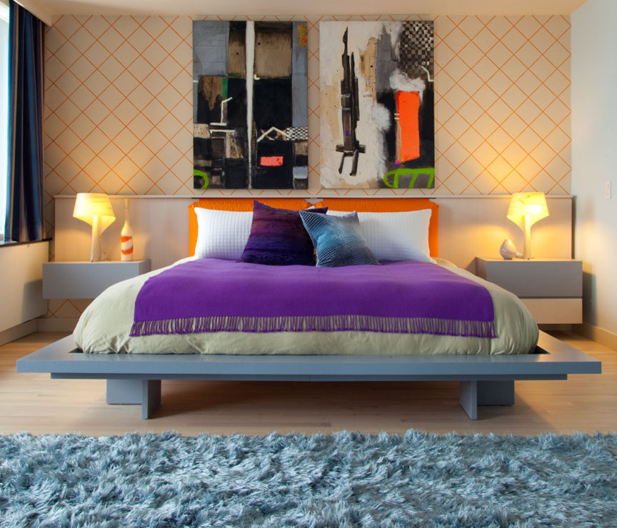 Large modern master bedroom in New York with orange walls and light hardwood flooring.