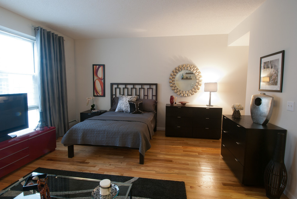 Kleines Modernes Schlafzimmer ohne Kamin, im Loft-Style mit weißer Wandfarbe und braunem Holzboden in New York