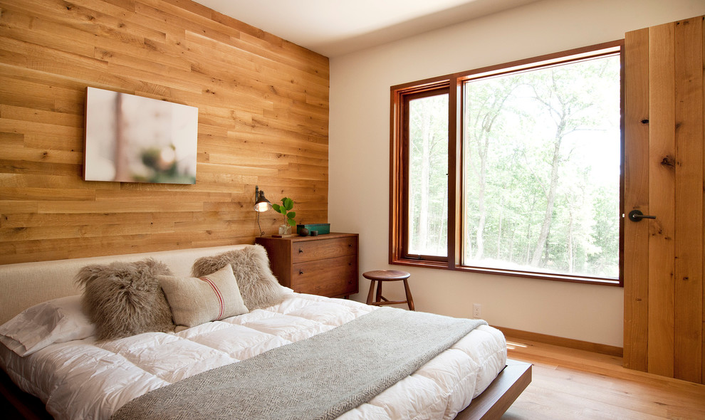 Cette image montre une chambre parentale design de taille moyenne avec un sol en bois brun et un mur blanc.