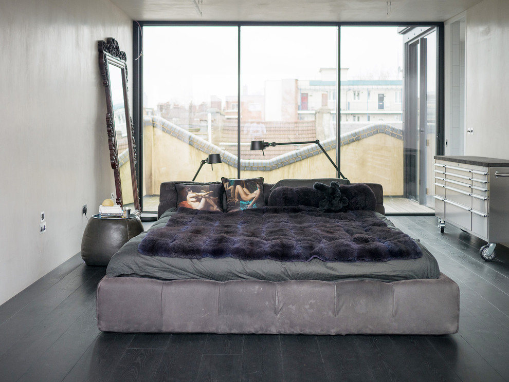 This is an example of a medium sized industrial bedroom in London with white walls, dark hardwood flooring and no fireplace.