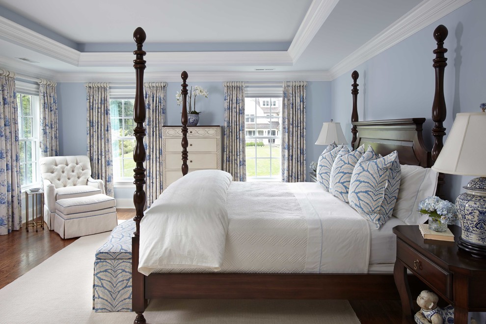 Klassisches Hauptschlafzimmer mit blauer Wandfarbe, braunem Holzboden, Kamin und Kaminumrandung aus Stein in Atlanta