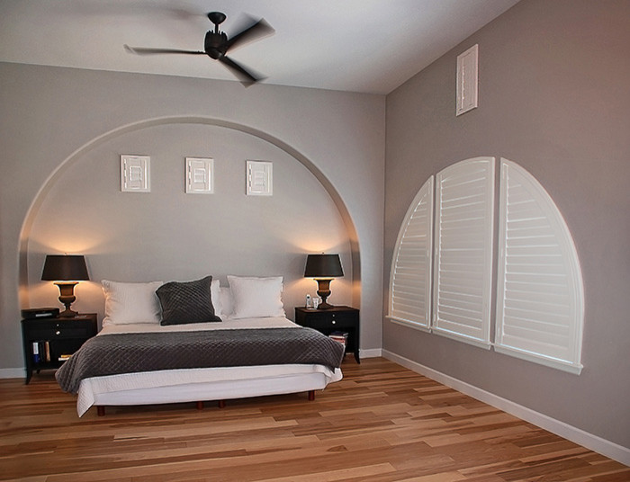 Imagen de dormitorio principal clásico renovado de tamaño medio sin chimenea con paredes grises, suelo de madera en tonos medios y suelo marrón