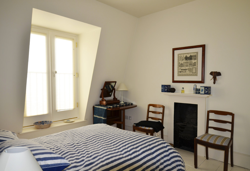 Foto di una grande camera da letto stile loft minimal con pareti bianche, pavimento in legno verniciato, camino classico e cornice del camino in intonaco