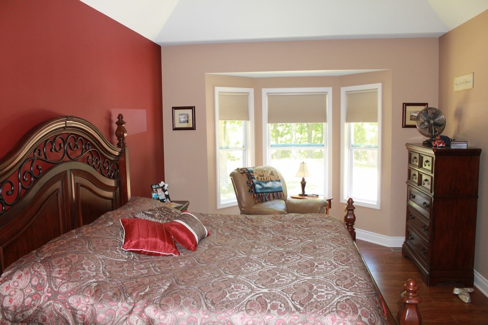 Exempel på ett klassiskt sovrum, med röda väggar och mellanmörkt trägolv