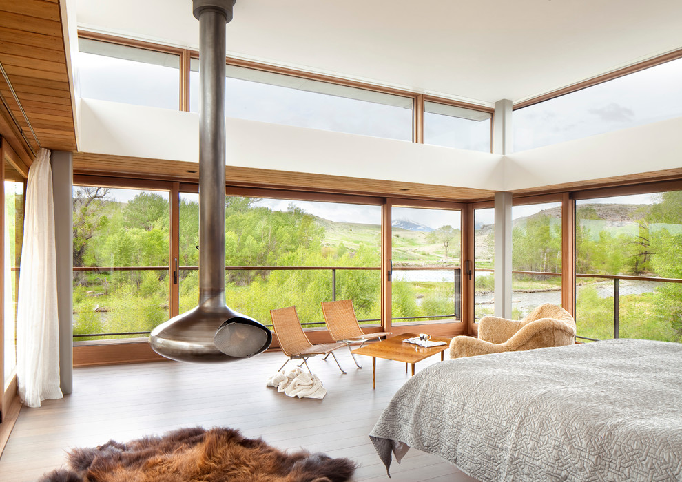 Ispirazione per una camera da letto moderna con parquet chiaro e stufa a legna