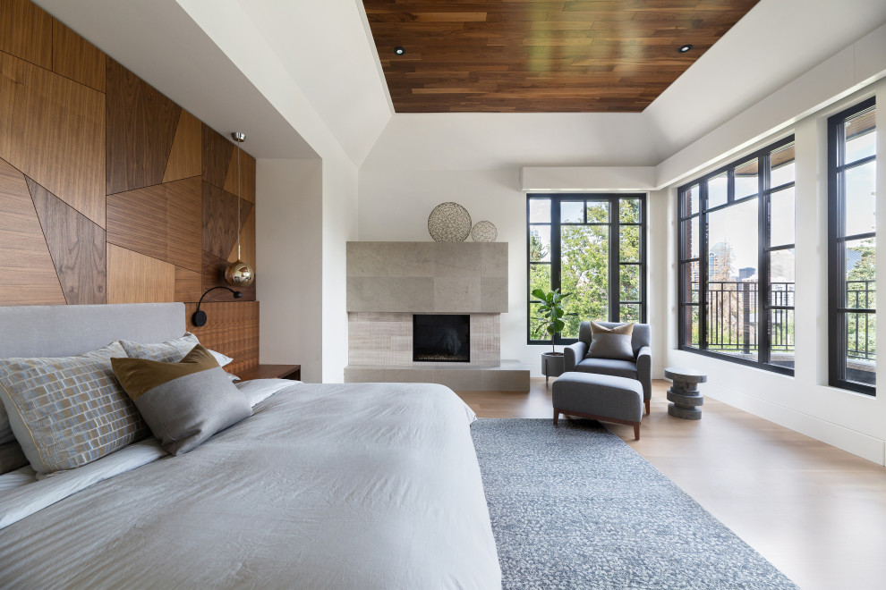 Modelo de dormitorio principal contemporáneo con paredes blancas, suelo de madera clara, chimenea de esquina, madera y madera
