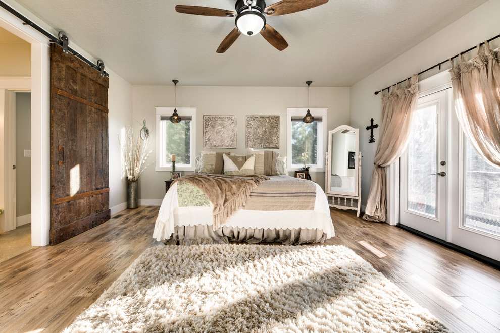 This is an example of a large farmhouse master bedroom in Orange County with grey walls, medium hardwood flooring, no fireplace and brown floors.