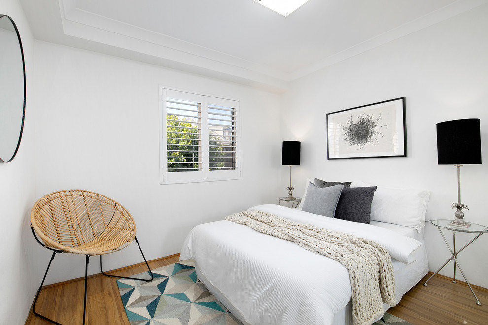 Modernes Gästezimmer ohne Kamin mit weißer Wandfarbe, Laminat und braunem Boden in Sydney