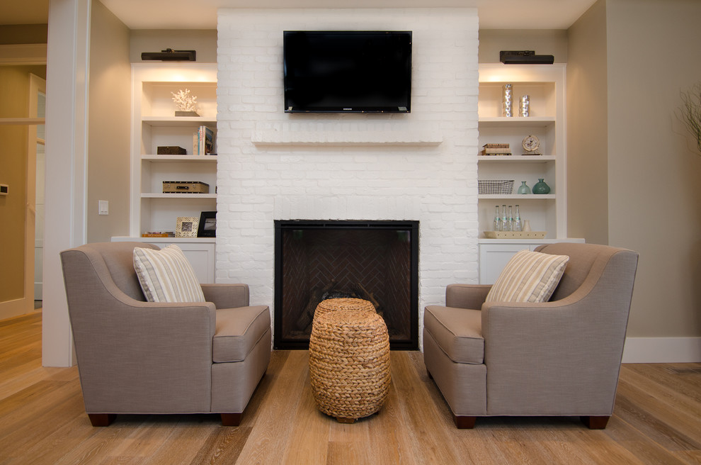 Idée de décoration pour une grande chambre parentale minimaliste avec un mur beige, un sol en bois brun, une cheminée standard et un manteau de cheminée en brique.