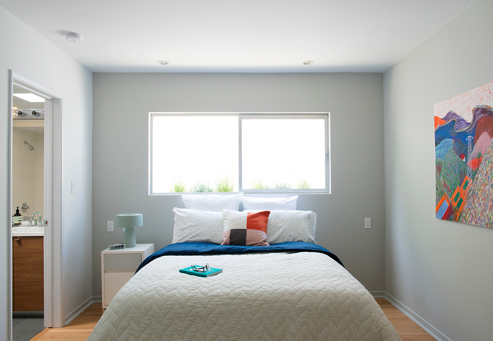 Aménagement d'une grande chambre d'amis moderne avec un mur gris, parquet clair, aucune cheminée et un sol marron.