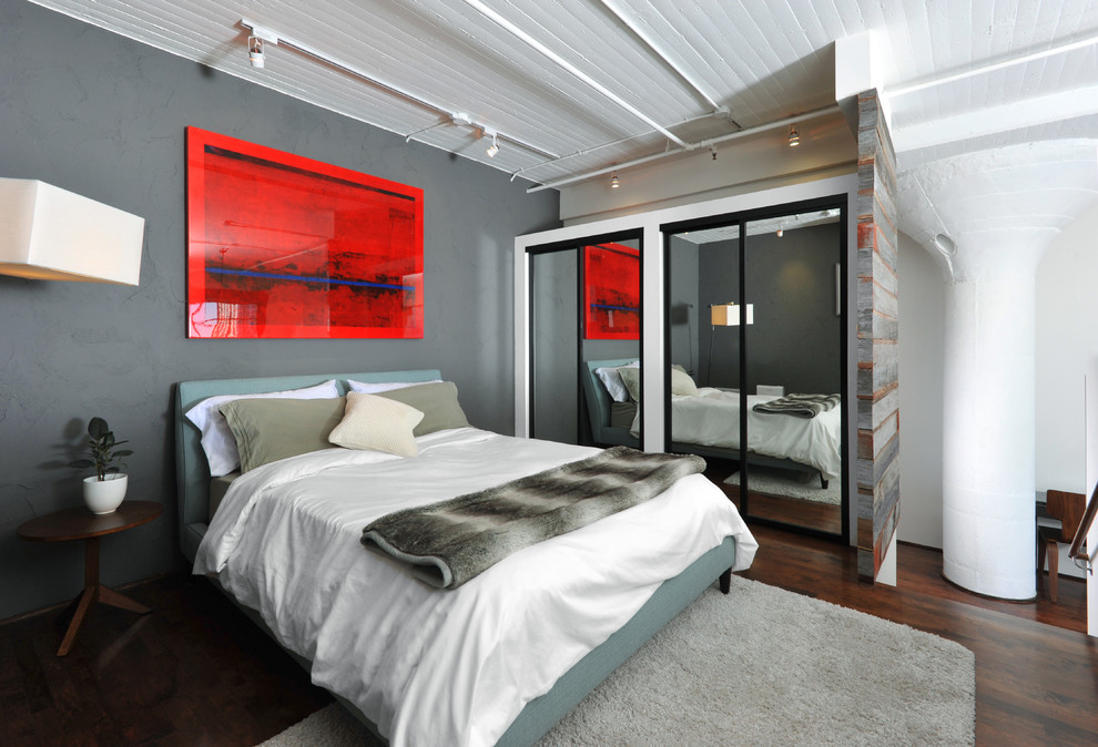 Immagine di una camera da letto stile loft industriale con pareti grigie e parquet scuro