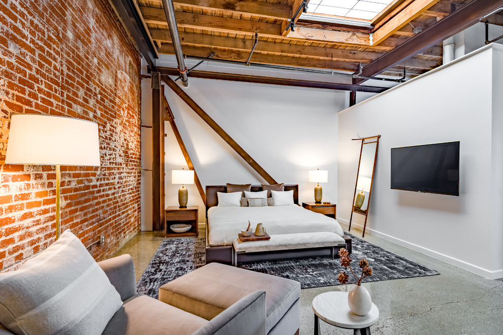 This is an example of an industrial grey and brown bedroom in Orange County with white walls, concrete flooring and grey floors.