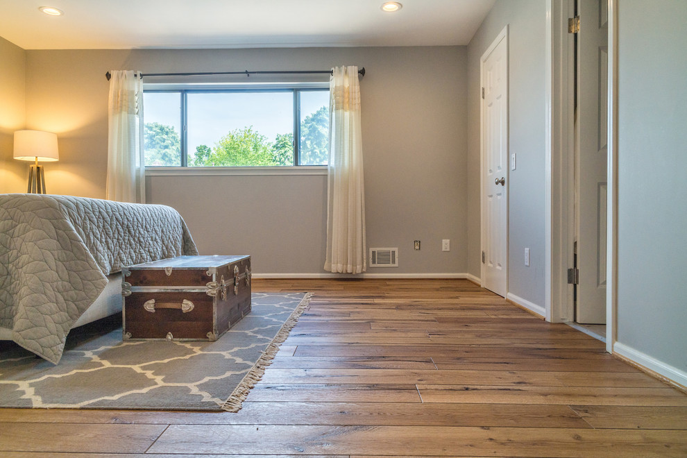 This is an example of a large rustic master and grey and brown bedroom in New York with grey walls, light hardwood flooring, brown floors and no fireplace.