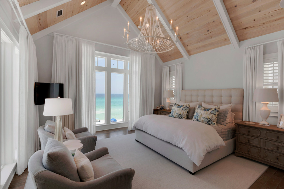 This is an example of a large coastal bedroom in Miami with white walls and light hardwood flooring.