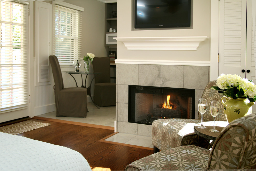 Exemple d'une chambre d'amis chic de taille moyenne avec un mur vert, parquet clair, une cheminée standard et un manteau de cheminée en pierre.