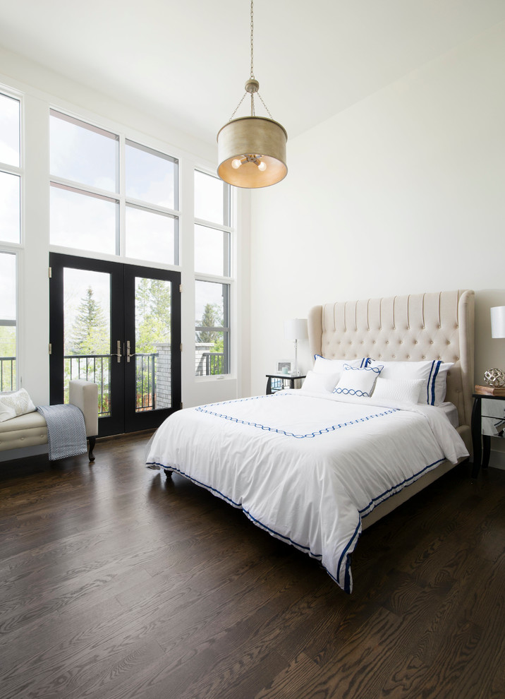 Modelo de dormitorio principal clásico renovado grande con paredes blancas, suelo de madera oscura y marco de chimenea de piedra