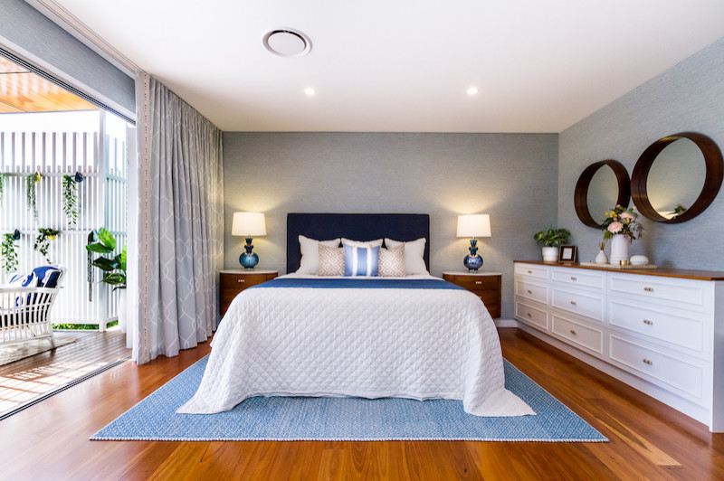 Large traditional master bedroom in Brisbane with green walls, medium hardwood flooring, brown floors and wallpapered walls.