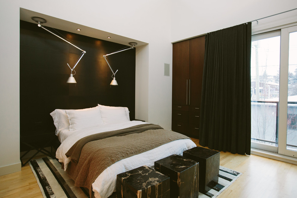 Exemple d'une chambre tendance avec un mur noir et parquet clair.